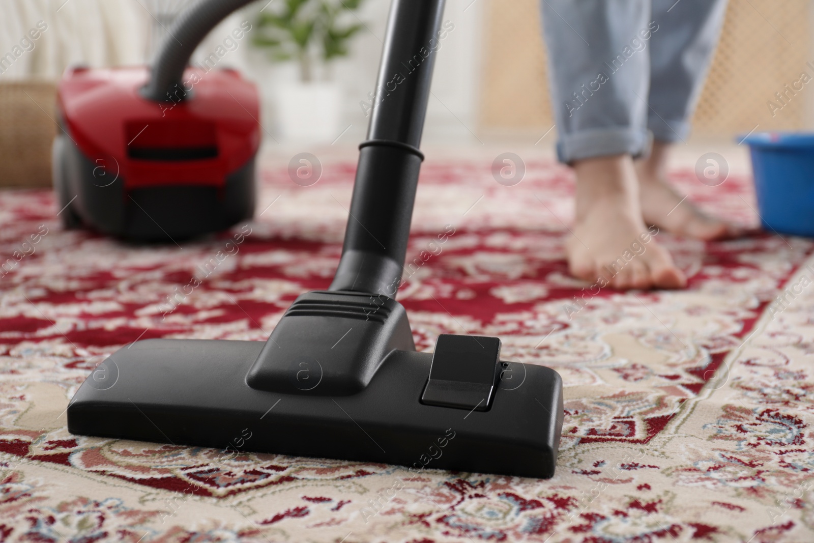 Photo of Woman cleaning carpet with vacuum cleaner at home, closeup. Space for text