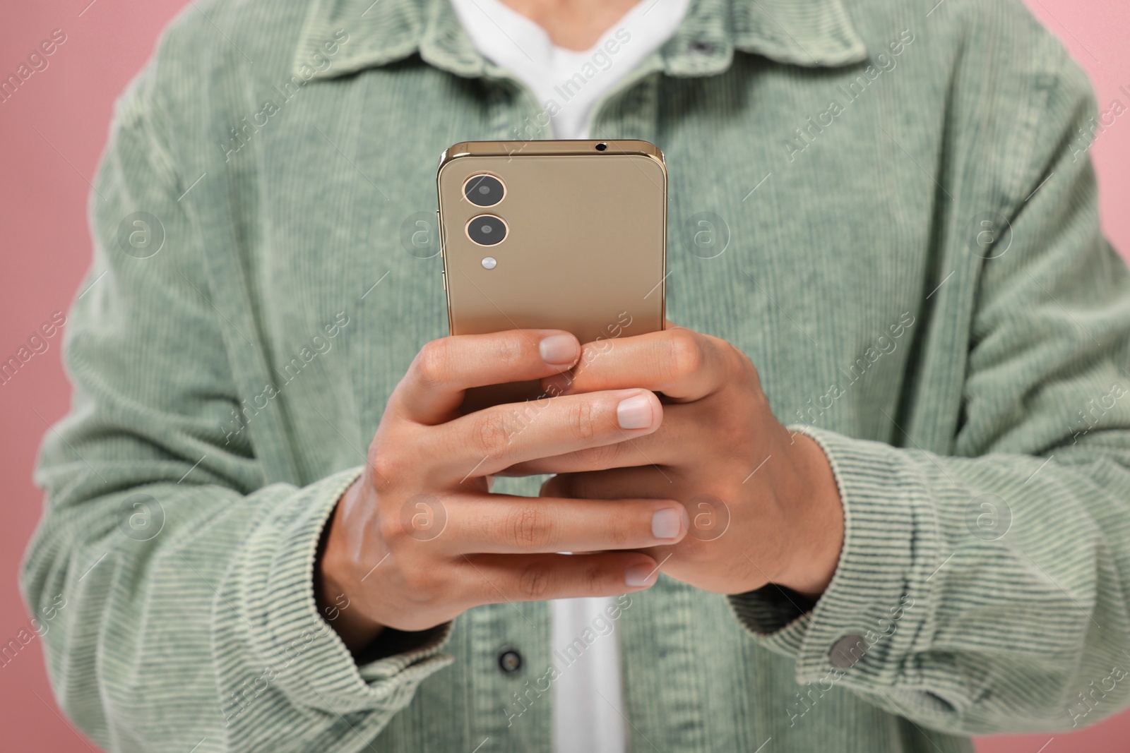 Photo of Man sending message via smartphone on pink background, closeup