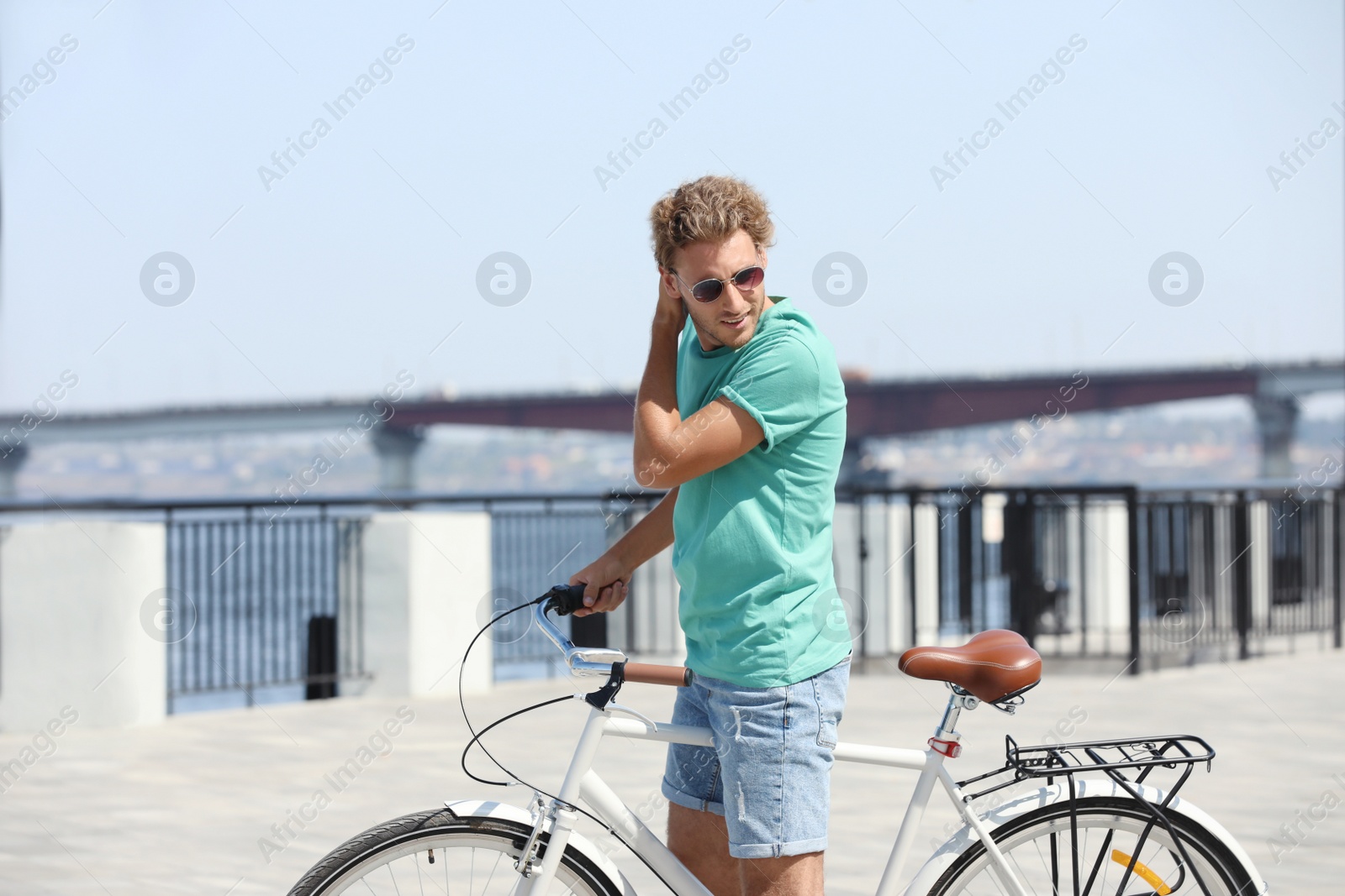 Photo of Handsome young man with bicycle outdoors on sunny day