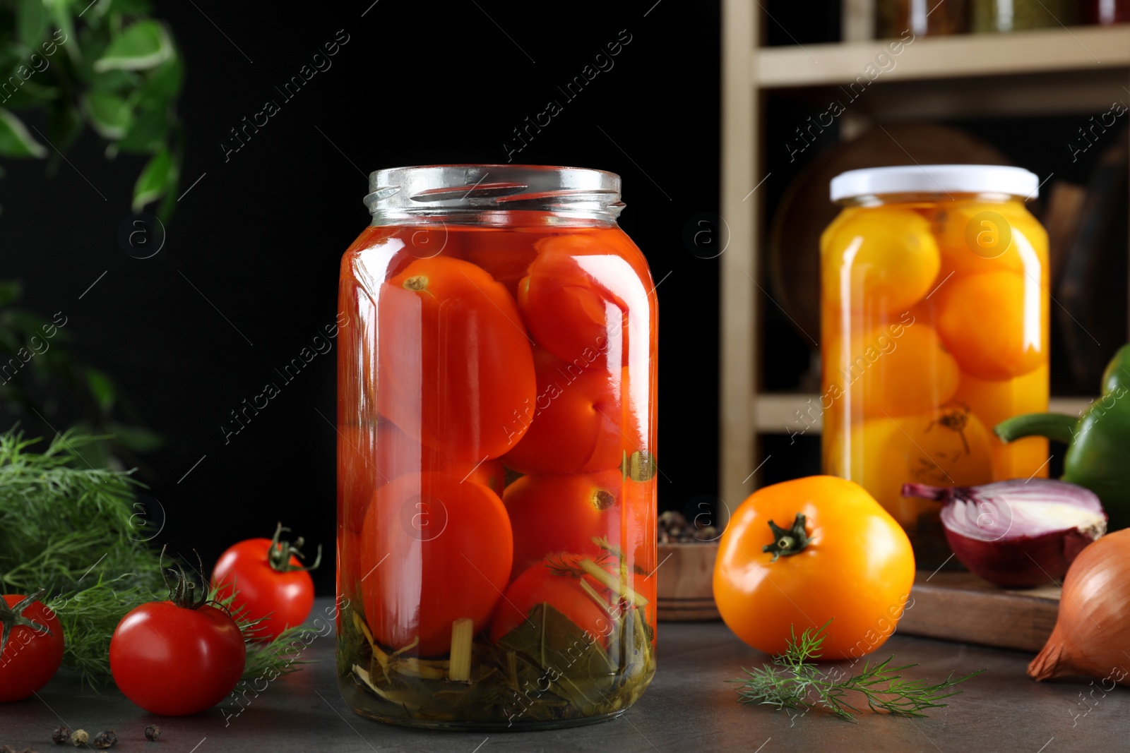 Photo of Glass jars of pickled tomatoes on grey table