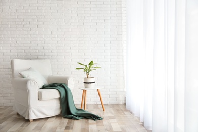 Comfortable armchair near brick wall in modern room interior. Space for text