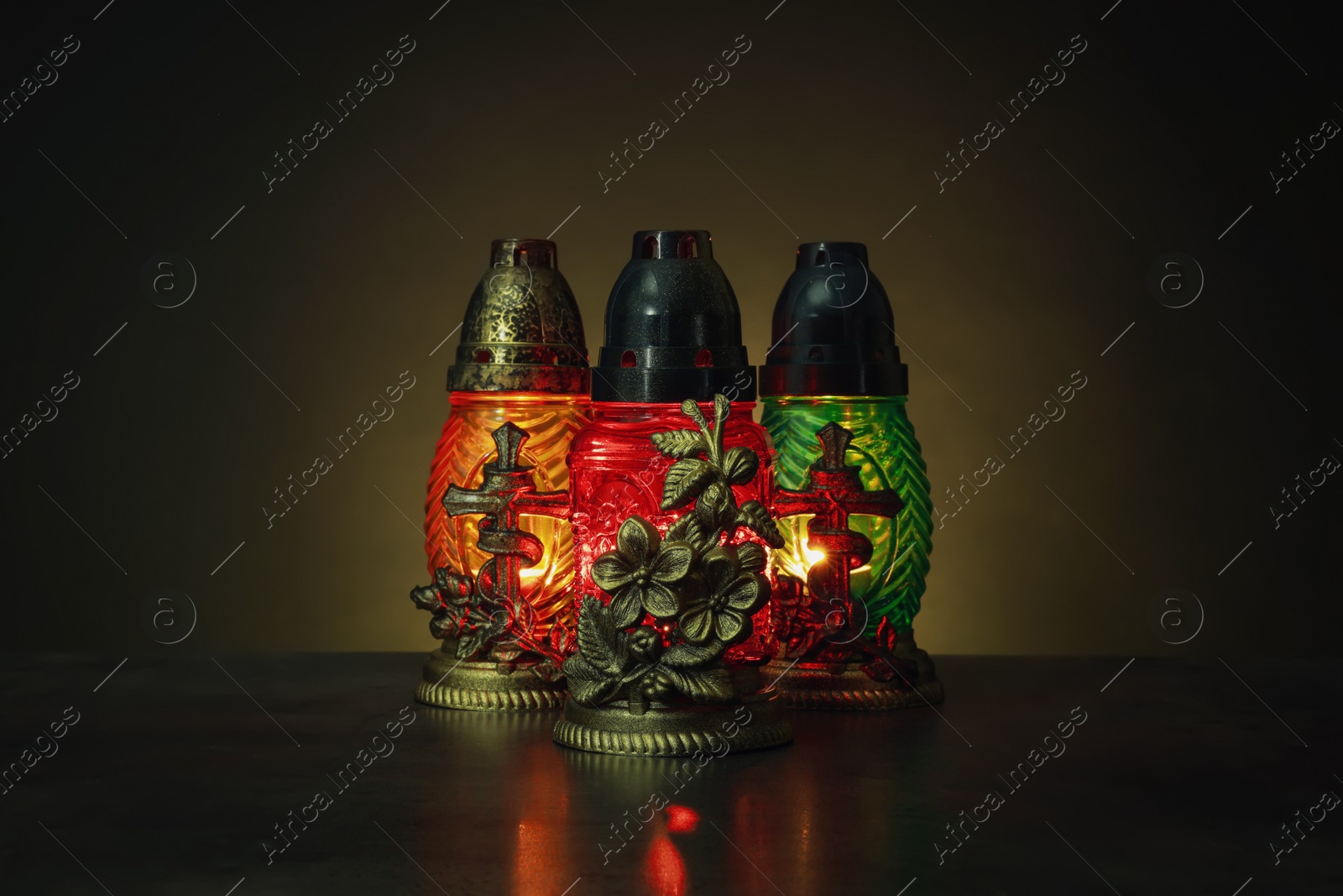 Photo of Beautiful glowing grave lights on table in darkness. Symbol of remembrance