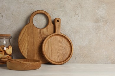 Photo of Wooden cutting boards, french palmier cookies, plate and spoons on white table near textured wall, space for text