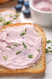 Photo of Tasty sandwiches with cream cheese and thyme on white wooden table, closeup