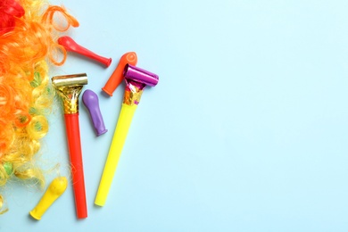Photo of Party blowers, balloons and clown wig on light blue background, flat lay. Space for text