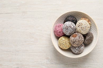 Photo of Different delicious vegan candy balls on white wooden table, top view. Space for text