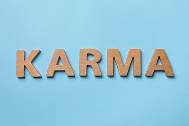Word Karma made with wooden letters on light blue background, top view
