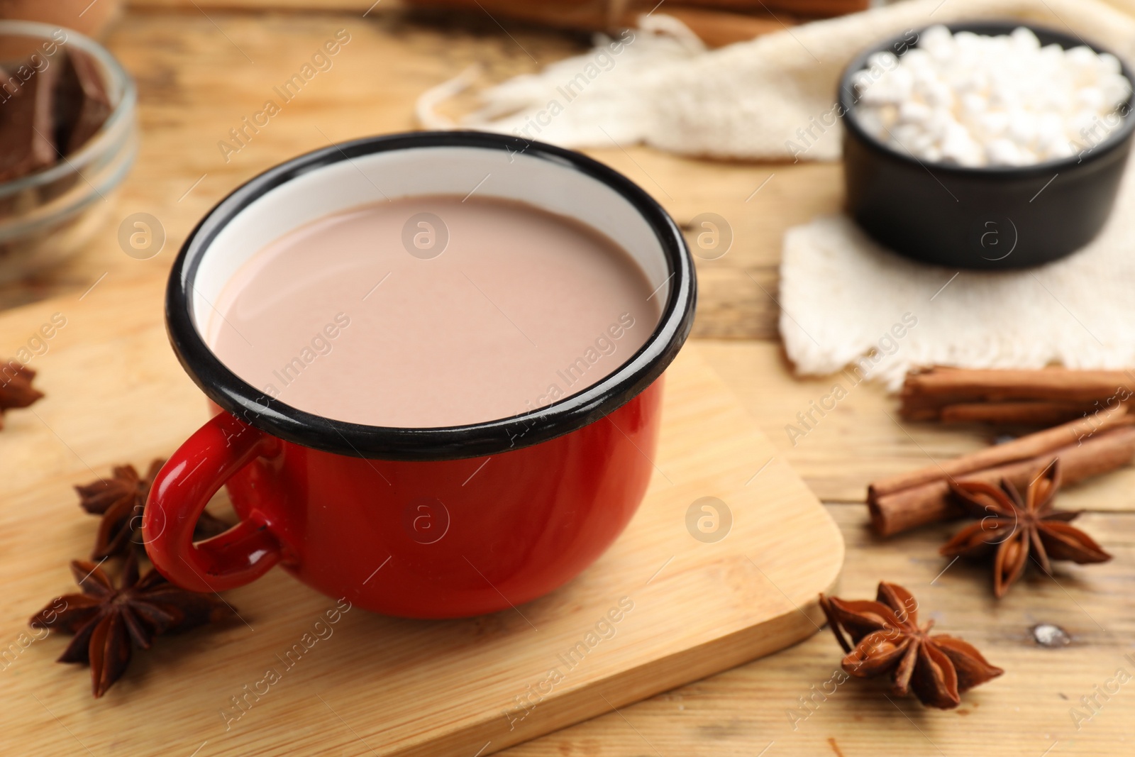 Photo of Tasty hot chocolate in cup and spices on wooden table, closeup