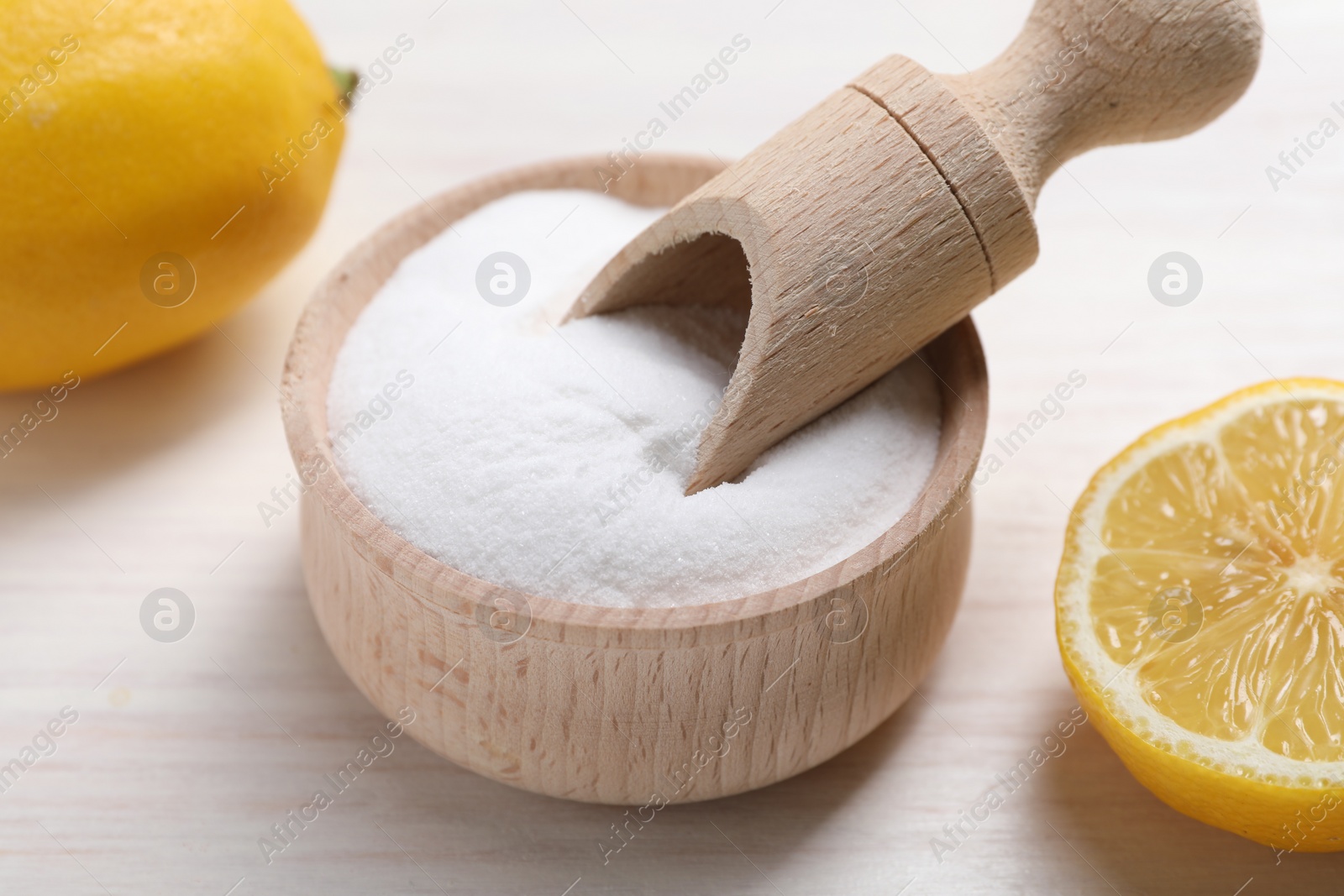 Photo of Baking soda and lemons on white wooden table, closeup