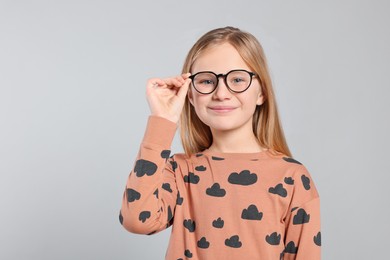 Photo of Portrait of cute girl in glasses on light grey background. Space for text