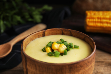 Photo of Delicious corn cream soup in wooden bowl, closeup