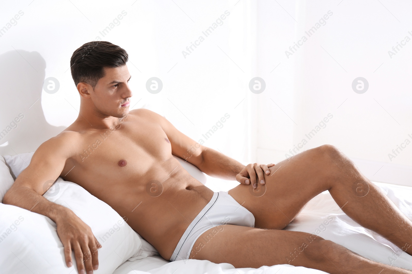 Photo of Handsome man in white underwear on bed indoors