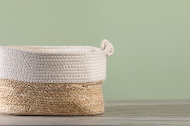 Empty wicker laundry basket near light green wall. Space for text