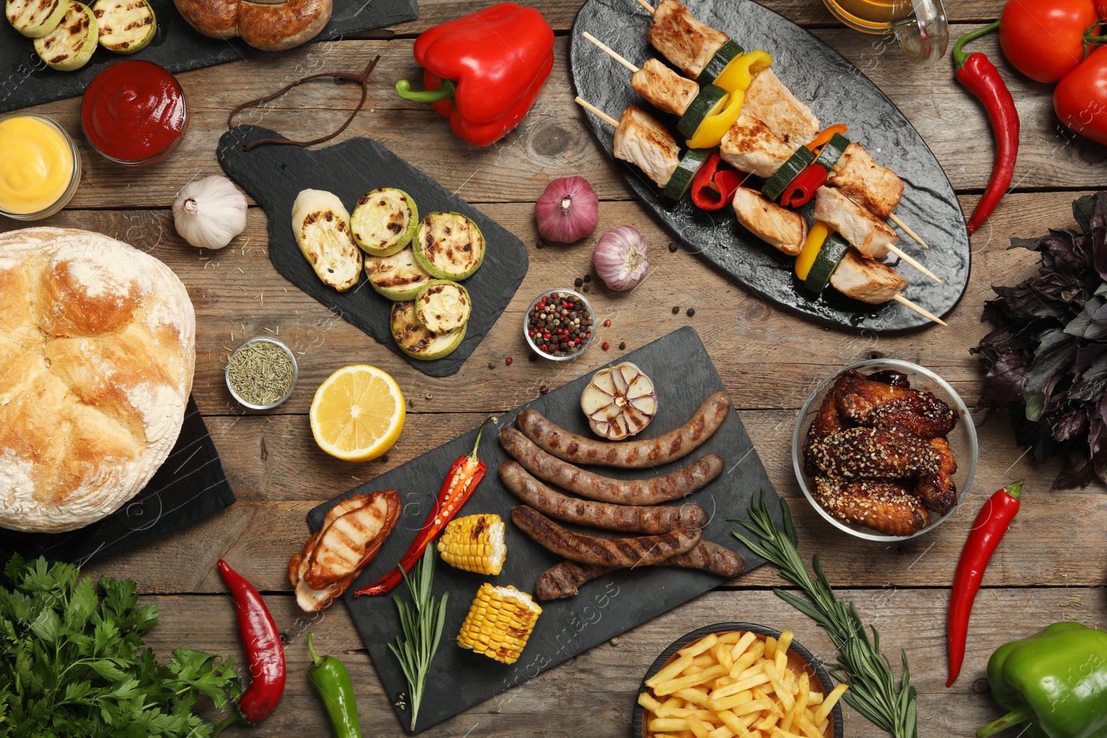 Photo of Flat lay composition with barbecued meat and vegetables on wooden table