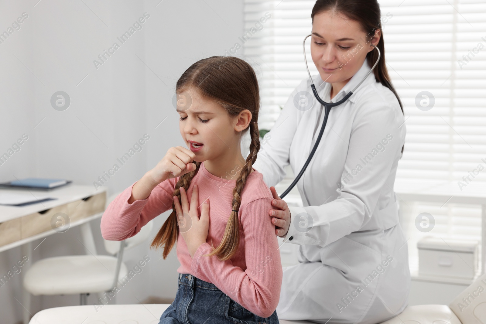 Photo of Doctor examining coughing girl in hospital. Cold symptoms