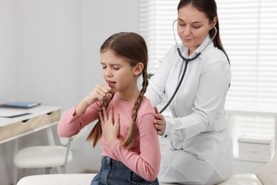 Photo of Doctor examining coughing girl in hospital. Cold symptoms