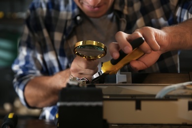 Photo of Repairman with magnifying glass and pliers fixing modern printer, closeup