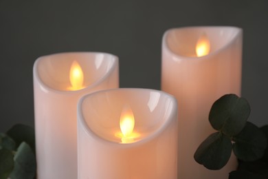 Photo of Decorative LED candles and eucalyptus on grey background, closeup