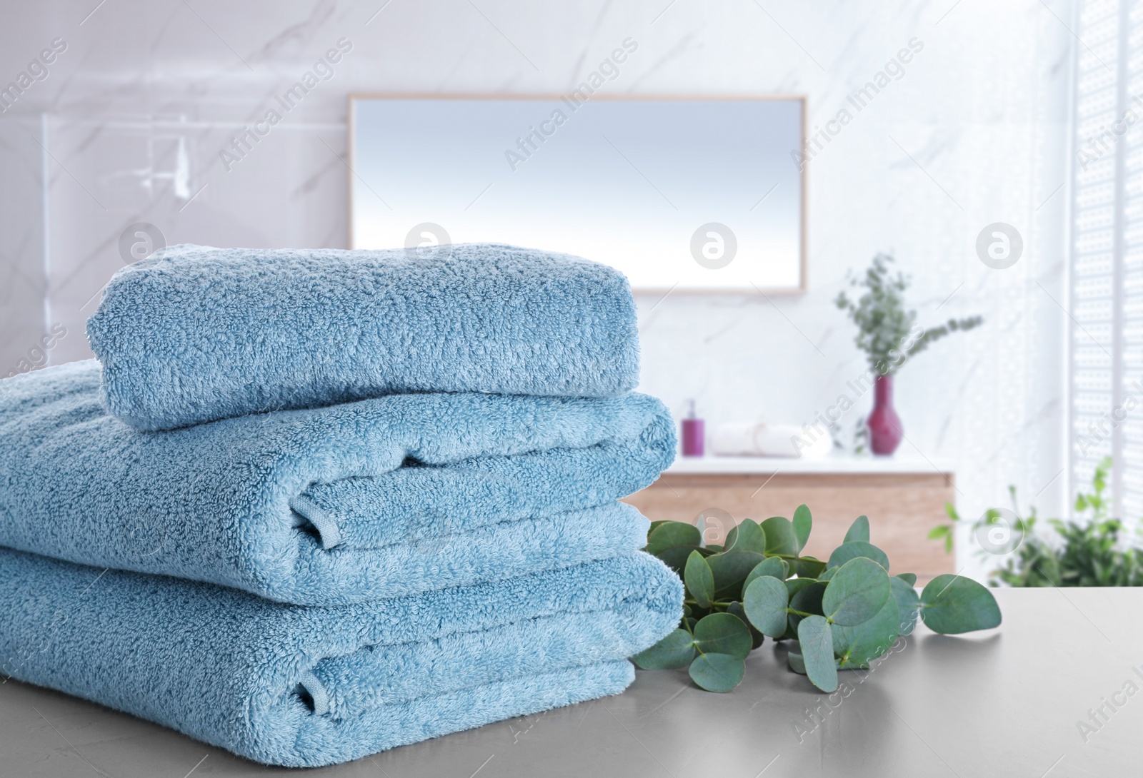 Image of Fresh towels and eucalyptus branches on light grey table in bathroom. Space for text