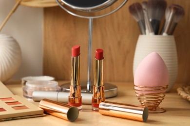 Makeup products and mirror on wooden dressing table