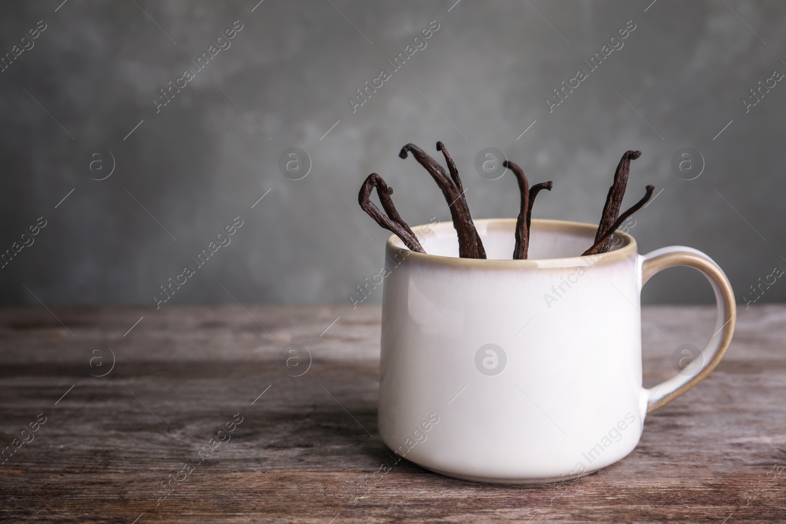 Photo of Vanilla sticks in cup on wooden table