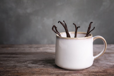 Vanilla sticks in cup on wooden table