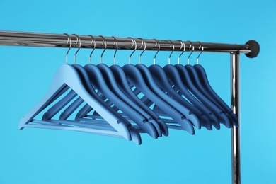 Photo of Metal rack with clothes hangers on color background