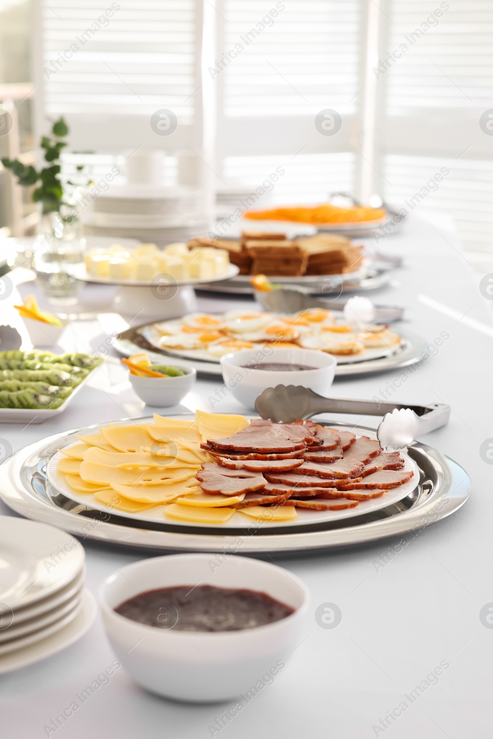 Photo of Different meals for breakfast on white table indoors. Buffet service