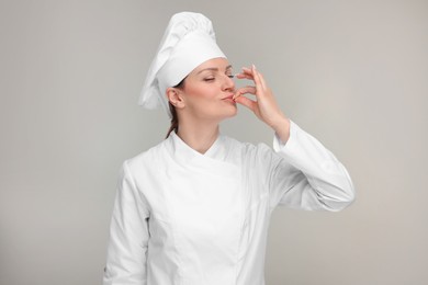 Woman chef in uniform showing perfect sign on grey background