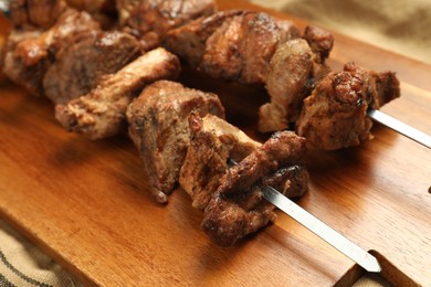 Photo of Delicious shish kebabs on wooden board, closeup