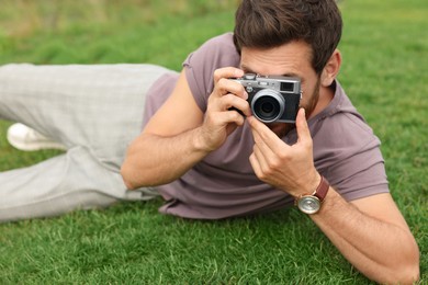 Man with camera taking photo on green grass. Interesting hobby