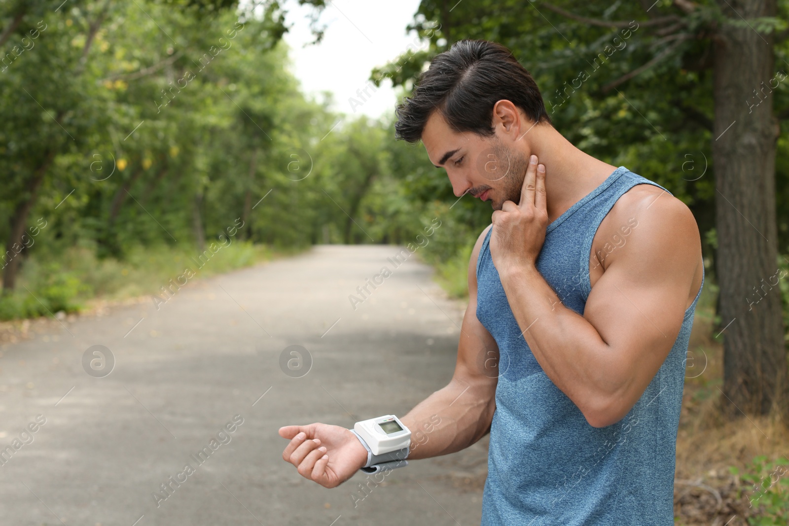 Photo of Young man checking pulse with medical device after training in park. Space for text