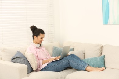 Photo of African American woman with laptop on sofa in room