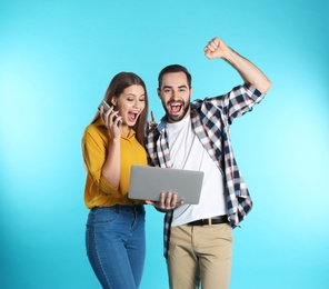 Photo of Emotional young people with laptop celebrating victory on color background