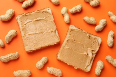 Photo of Tasty peanut butter sandwiches and peanuts on orange background, flat lay