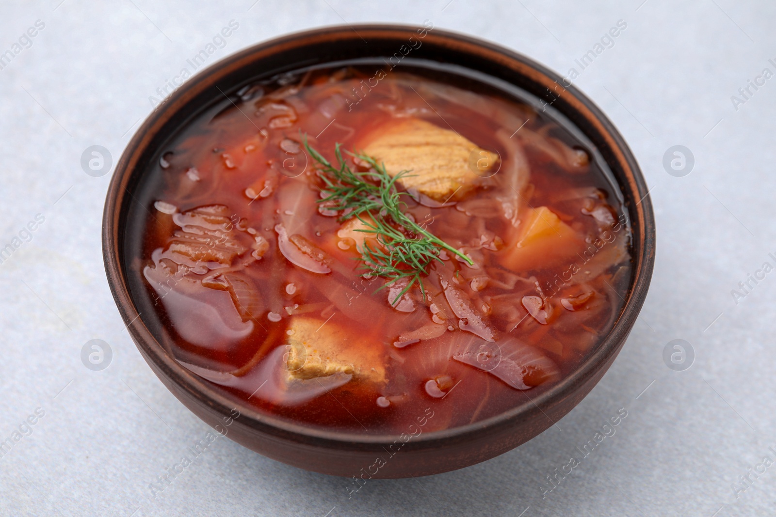 Photo of Bowl of delicious borscht on white table