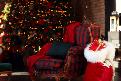 Santa Claus bag near armchair in room with Christmas tree
