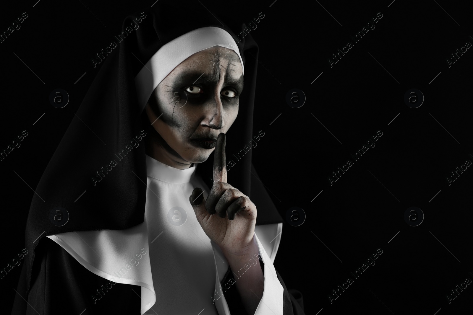 Photo of Portrait of scary devilish nun on black background, space for text. Halloween party look