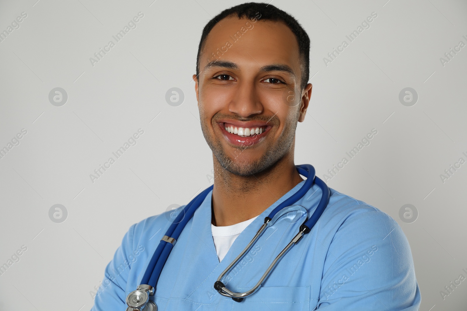 Photo of Doctor or medical assistant (male nurse) in uniform with stethoscope on light grey background