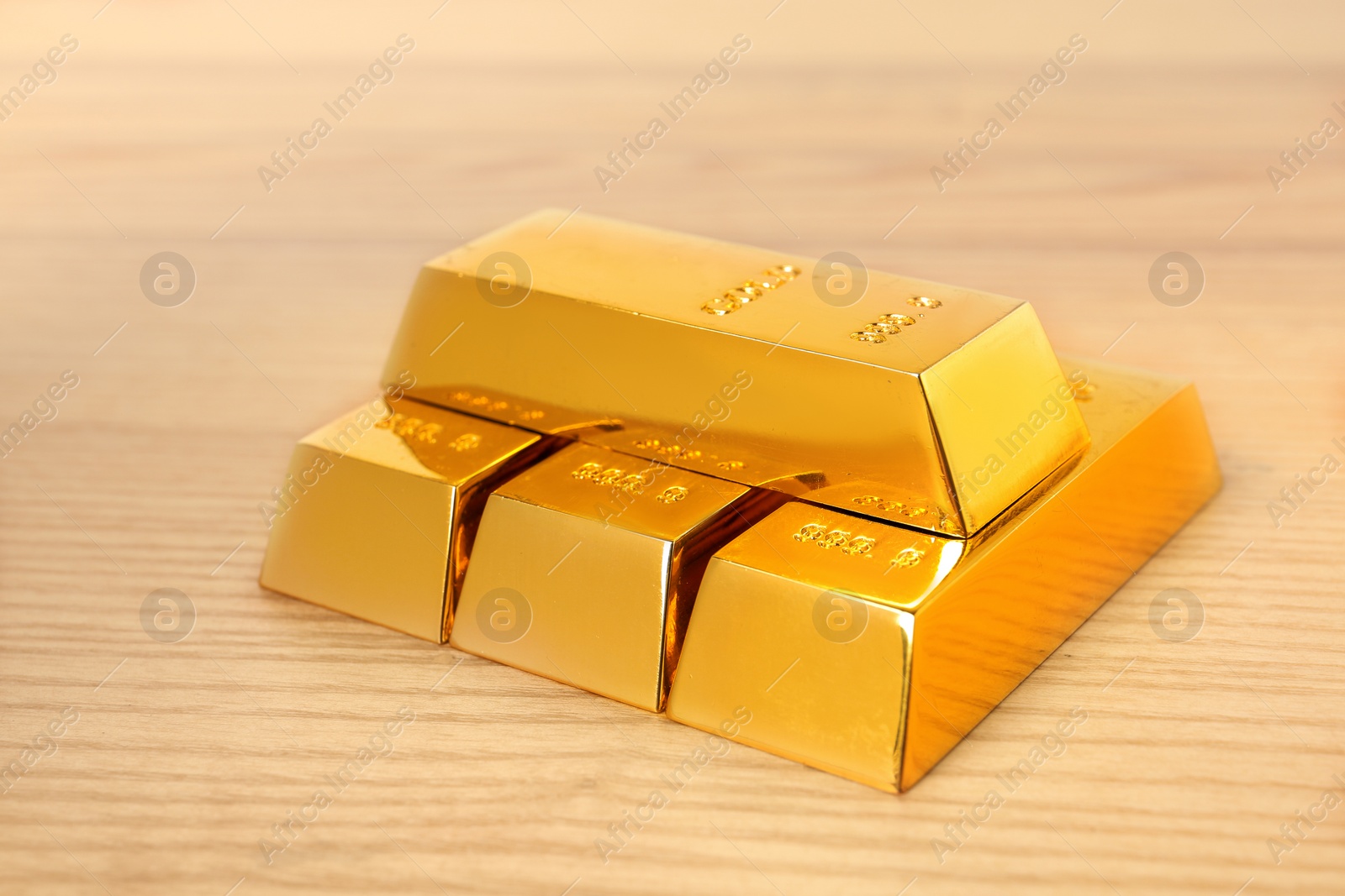 Photo of Stacked shiny gold bars on wooden table