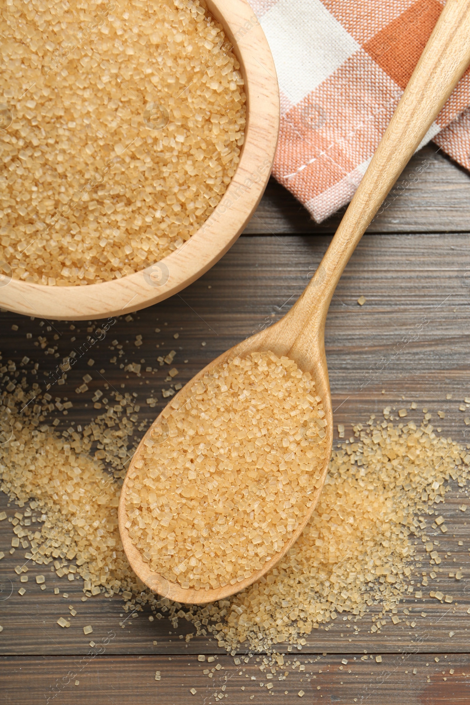 Photo of Brown sugar in bowl and spoon on wooden table, flat lay