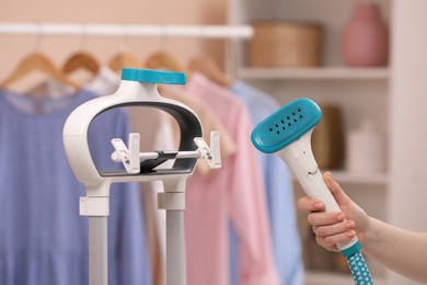 Woman with modern steam iron at home, closeup