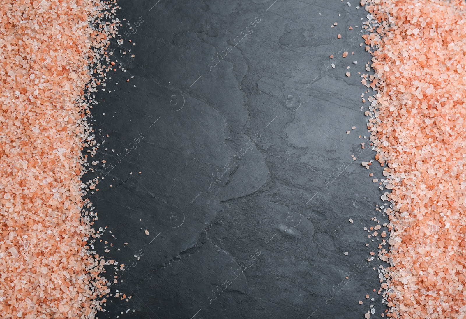 Photo of Frame of pink himalayan salt on black table, flat lay. Space for text