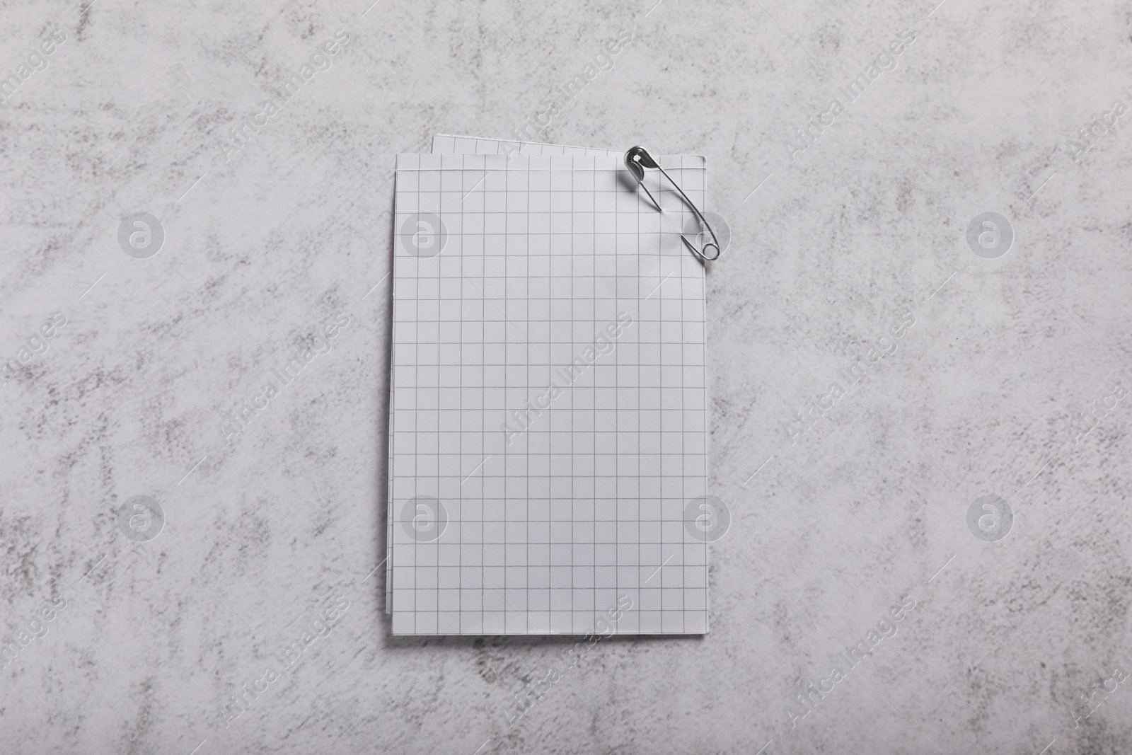 Photo of Sheets of paper attached with safety pin on grey textured background, top view