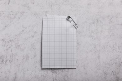 Photo of Sheets of paper attached with safety pin on grey textured background, top view