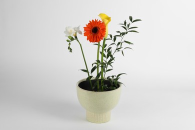Stylish ikebana as house decor. Beautiful fresh flowers in pot on white background