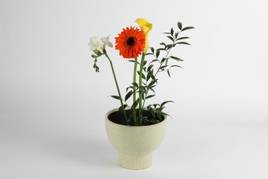 Photo of Stylish ikebana as house decor. Beautiful fresh flowers in pot on white background