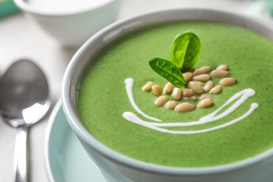 Cup of healthy green soup with fresh spinach on table, closeup