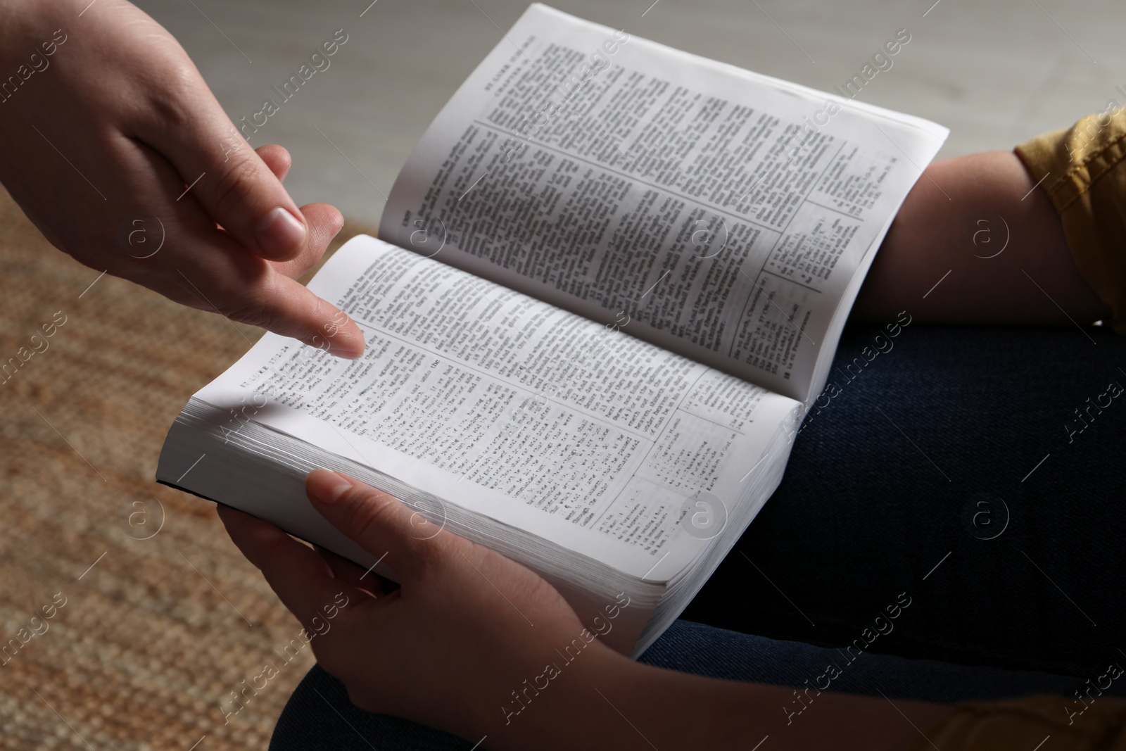 Photo of Woman showing psalm in Bible to man indoors, closeup