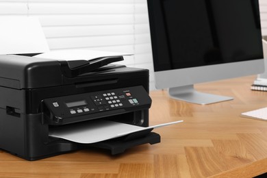 Photo of Modern printer with paper on wooden desk indoors. Space for text
